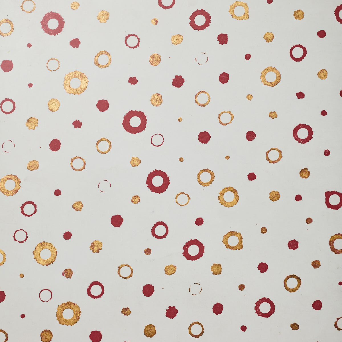 Detail of wallpaper in an irregular polka dot print in shades of gold and red on a white field.