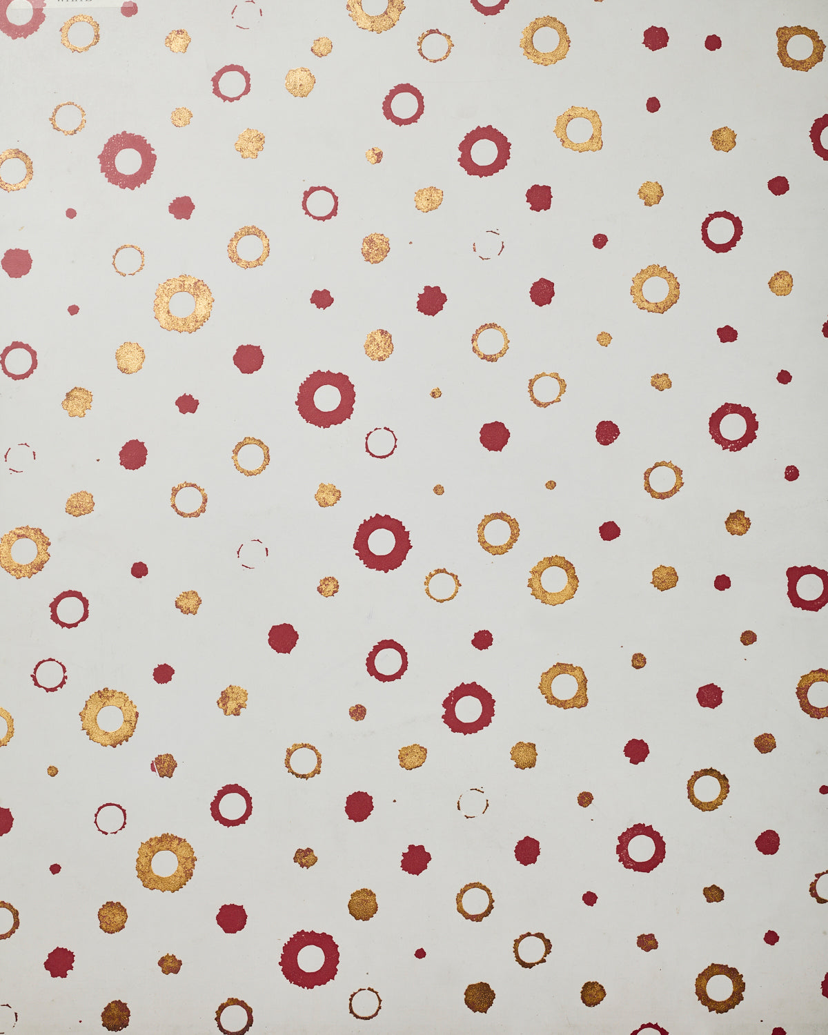 Detail of wallpaper in an irregular polka dot print in shades of gold and red on a white field.