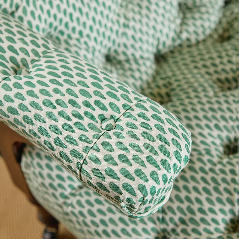 Close-up of an armchair upholstered in a painterly teardrop print in green on a white field.