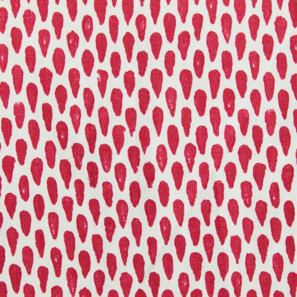 Detail of fabric in a painterly teardrop print in red on a cream field.