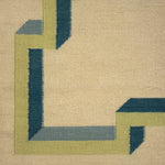 Close-up of a geometric patterned rug with green and blue lines on a beige background