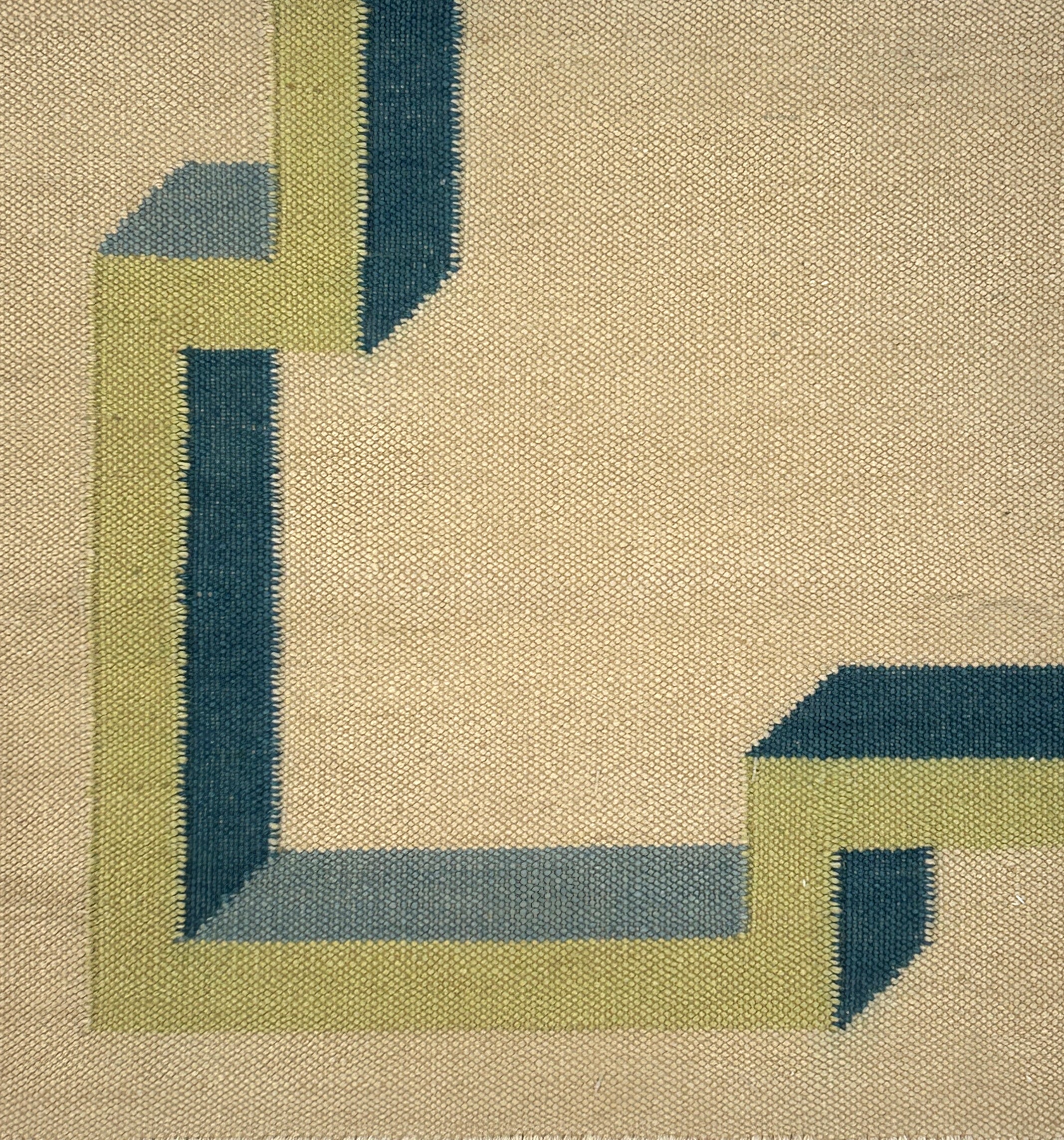 Close-up of a geometric patterned rug with green and blue lines on a beige background