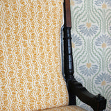 Chair with yellow floral patterned fabric against a floral wallpaper background