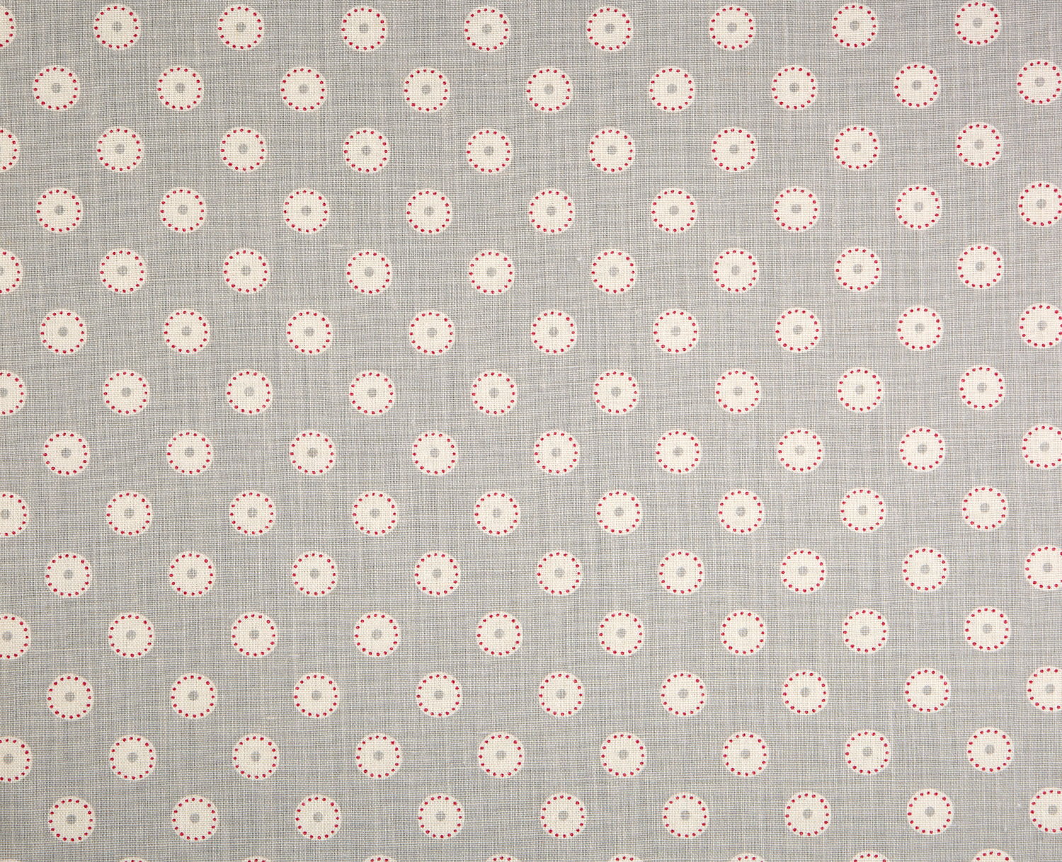 Detail of fabric in a playful dot print in pink and cream on a gray field.