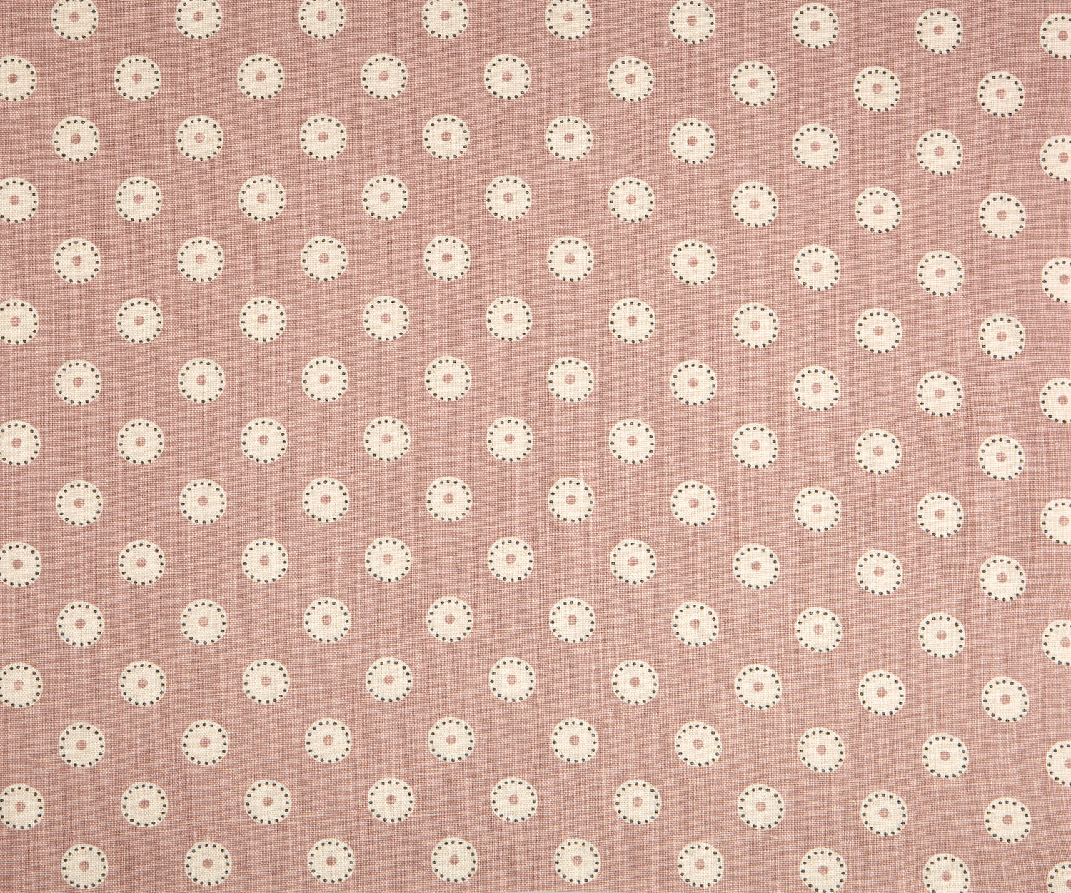 Detail of fabric in a playful dot print in gray and white on a mauve field.