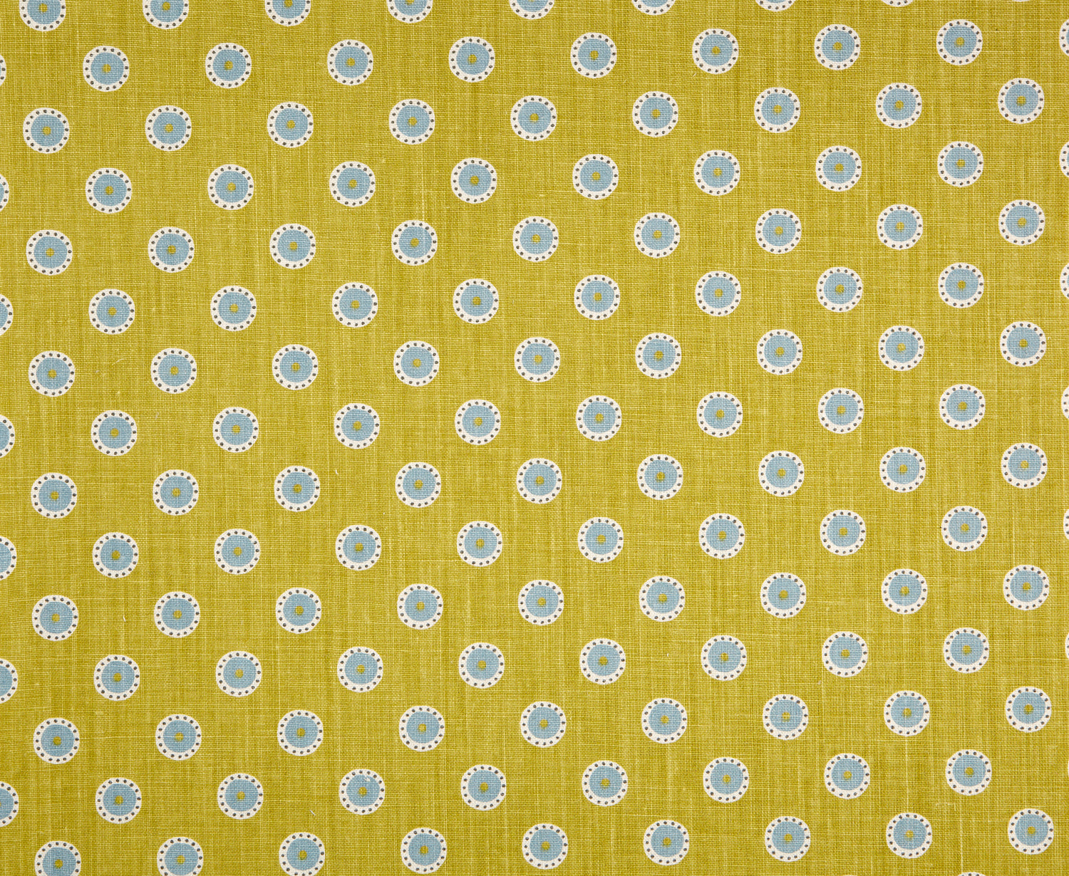 Detail of fabric in a playful dot print in blue and white on a mustard field.