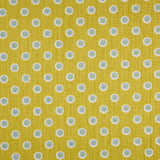 Detail of fabric in a playful dot print in blue and white on a mustard field.