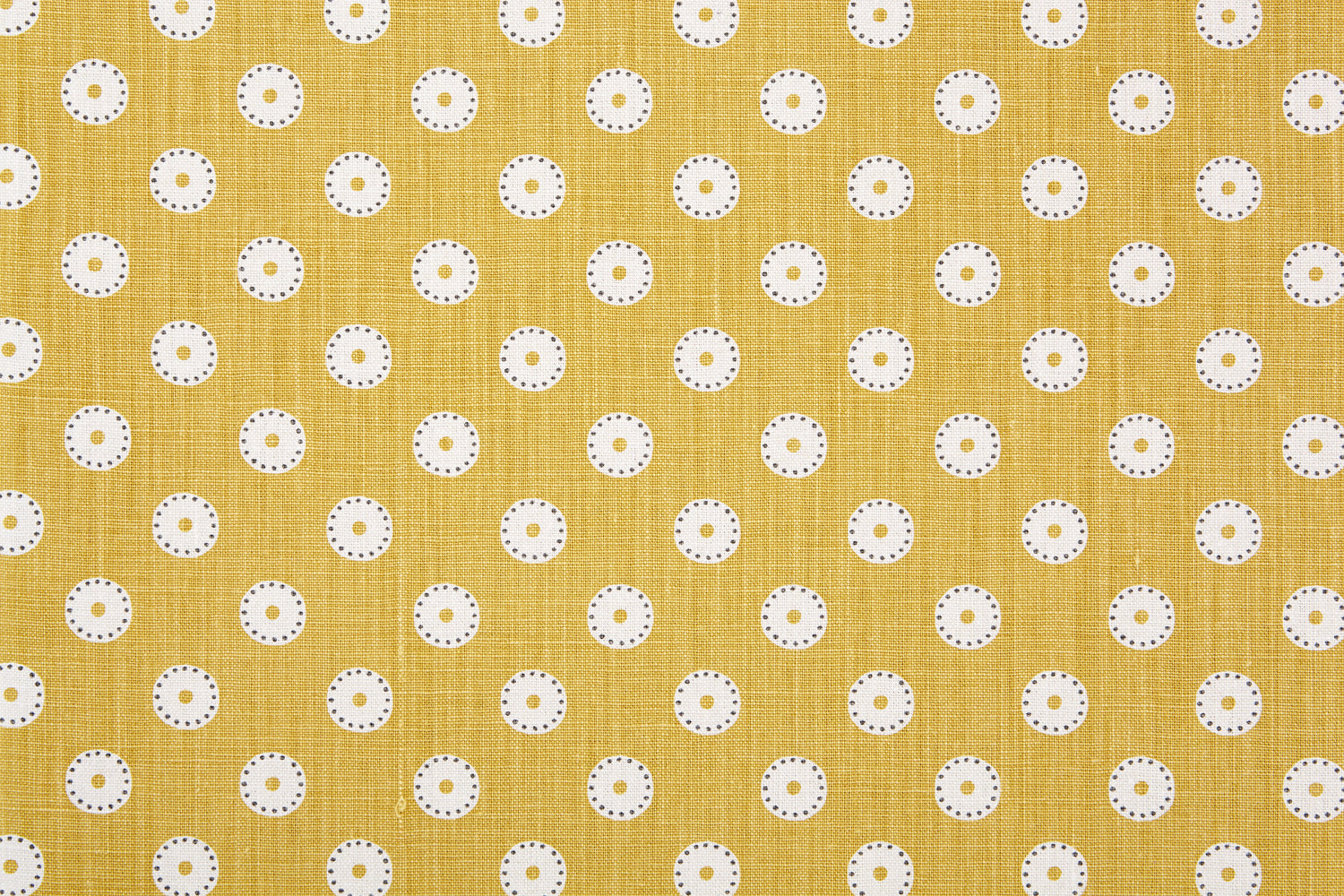 Detail of fabric in a playful dot print in white and gray on a mustard field.