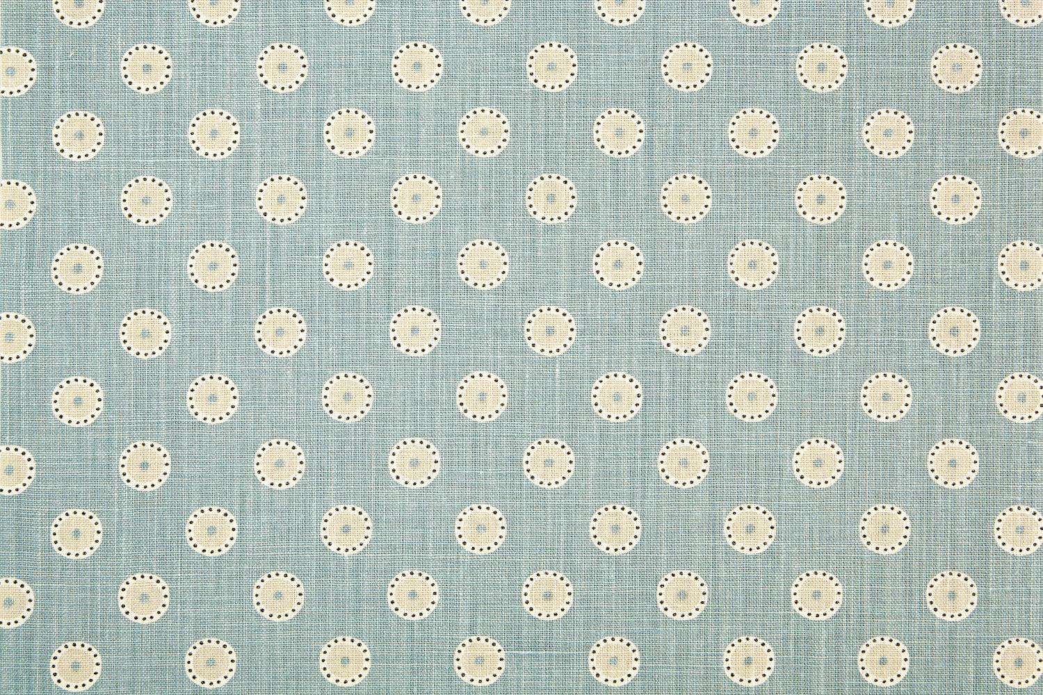 Detail of fabric in a playful dot print in white, gray and tan on a blue field.