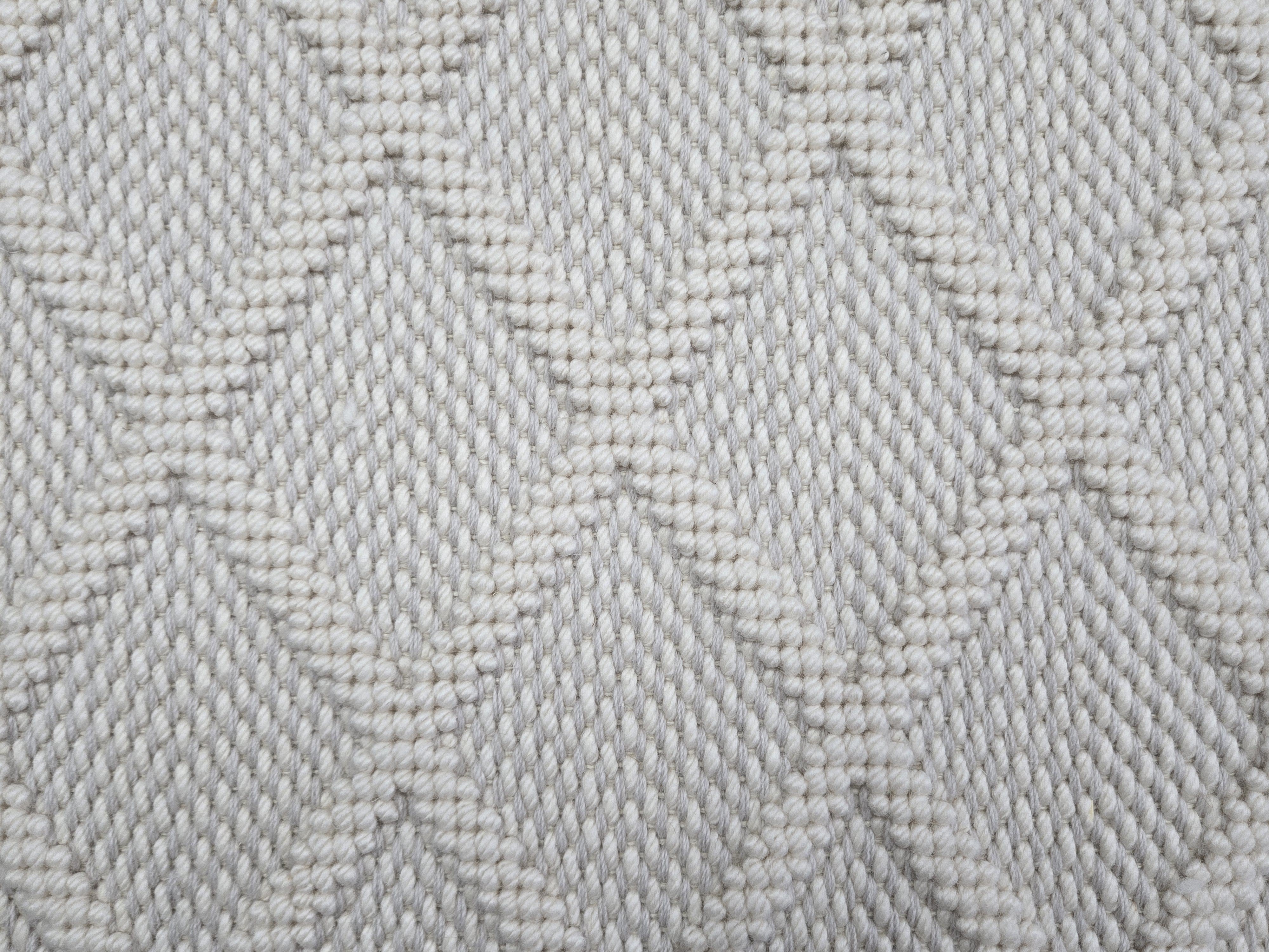 Broadloom carpet in a dimension diamond lattice in cream and light grey. 