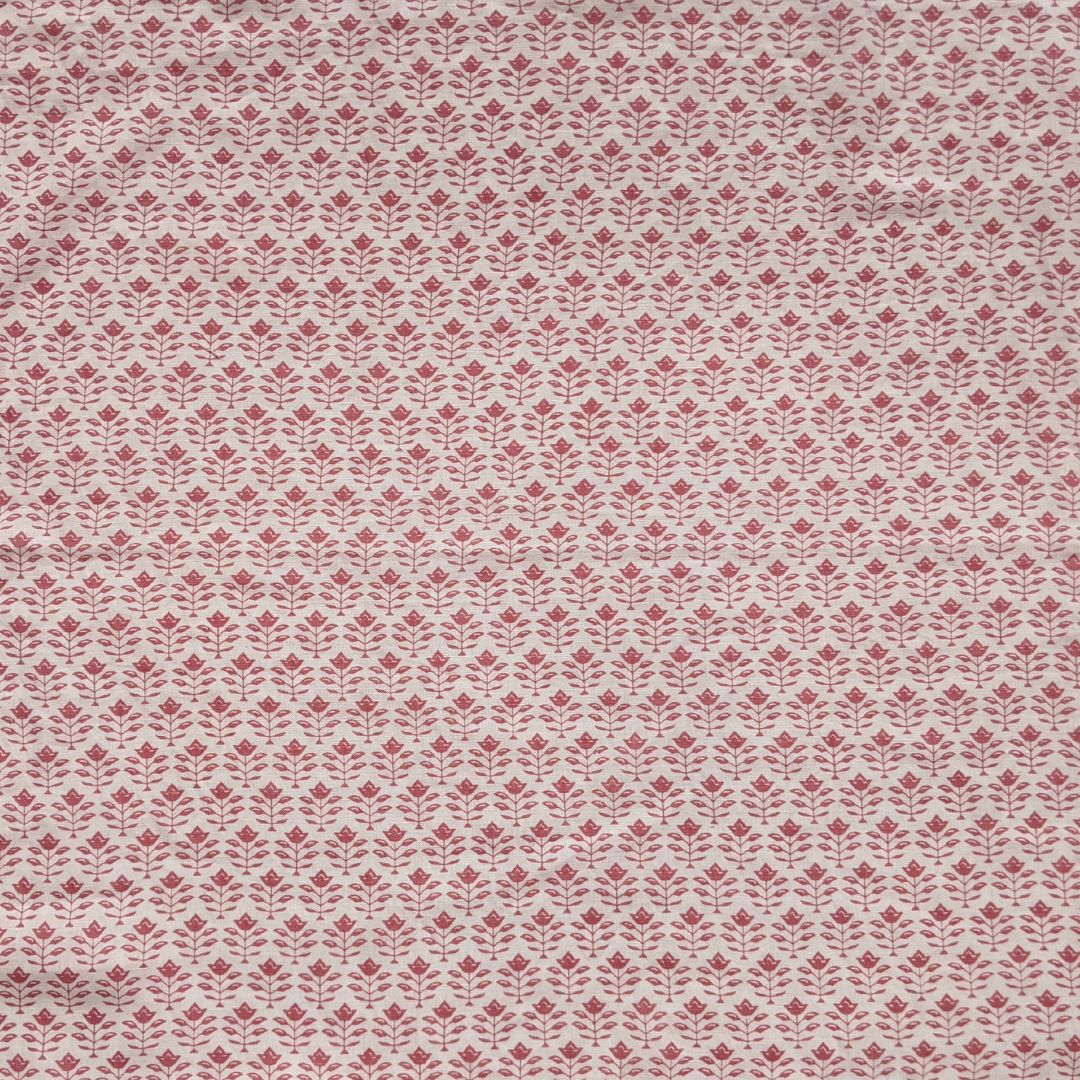 Detail of fabric in a small-scale floral grid print in red on a cream field.