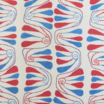 Detail of fabric in an abstract floral stripe in red and blue on a cream field.