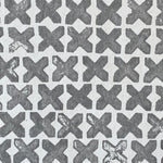 Close-up of wallpaper in a repeating "X" print in gray on a white field.