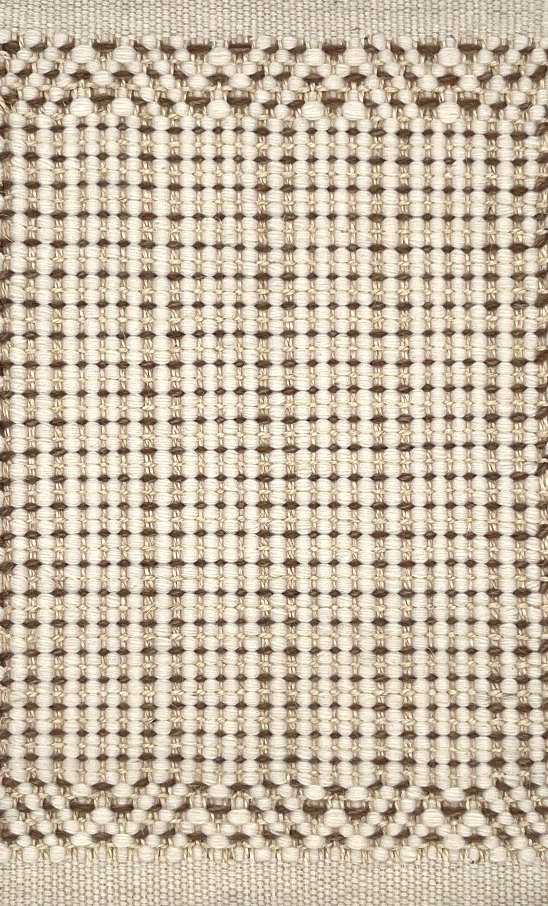 Close-up of a textured handmade rug with a grid pattern in beige and brown.