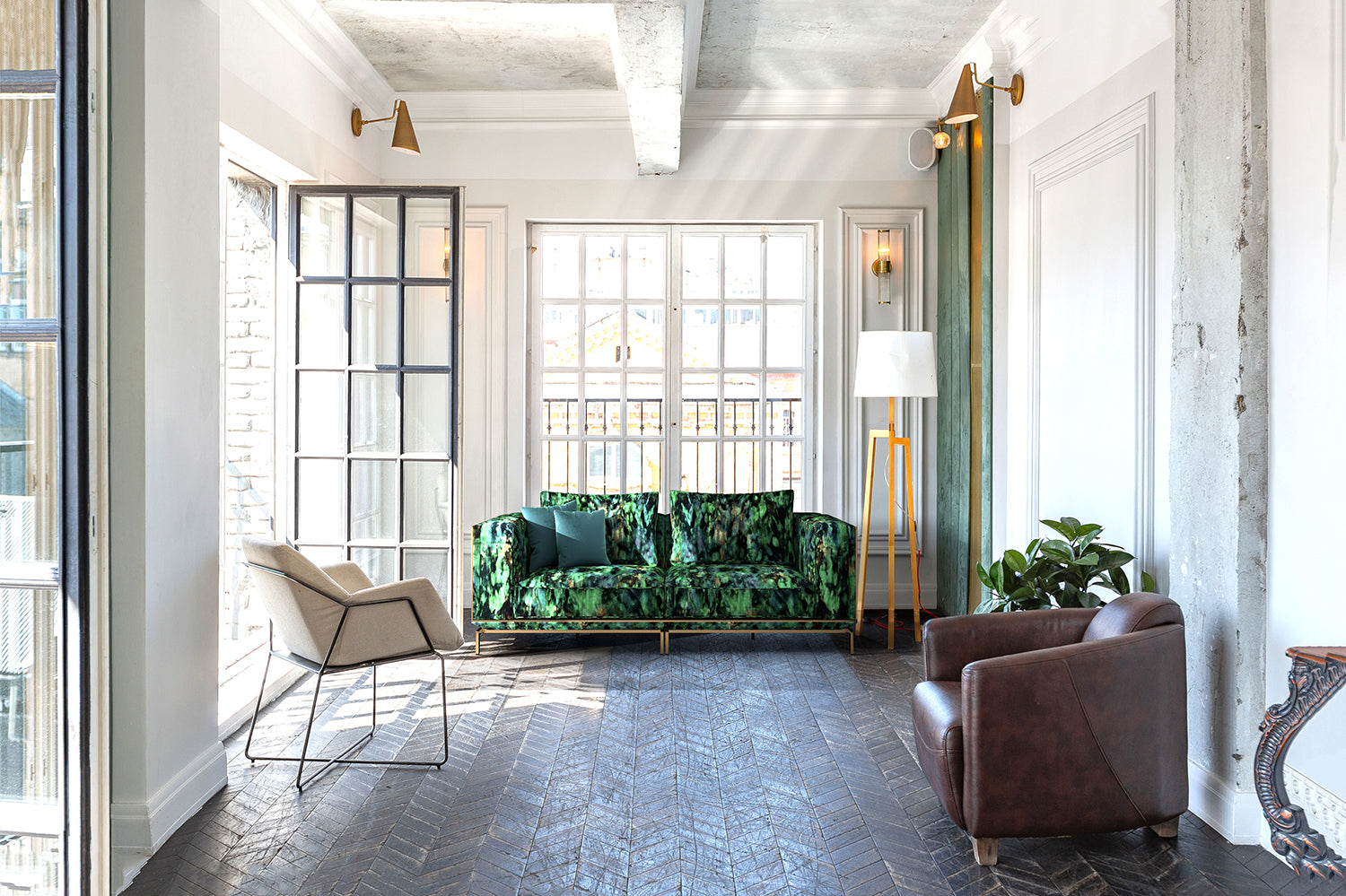 A sunny living space with large open doors and a sofa upholstered in an abstract ink blot print in black and green.