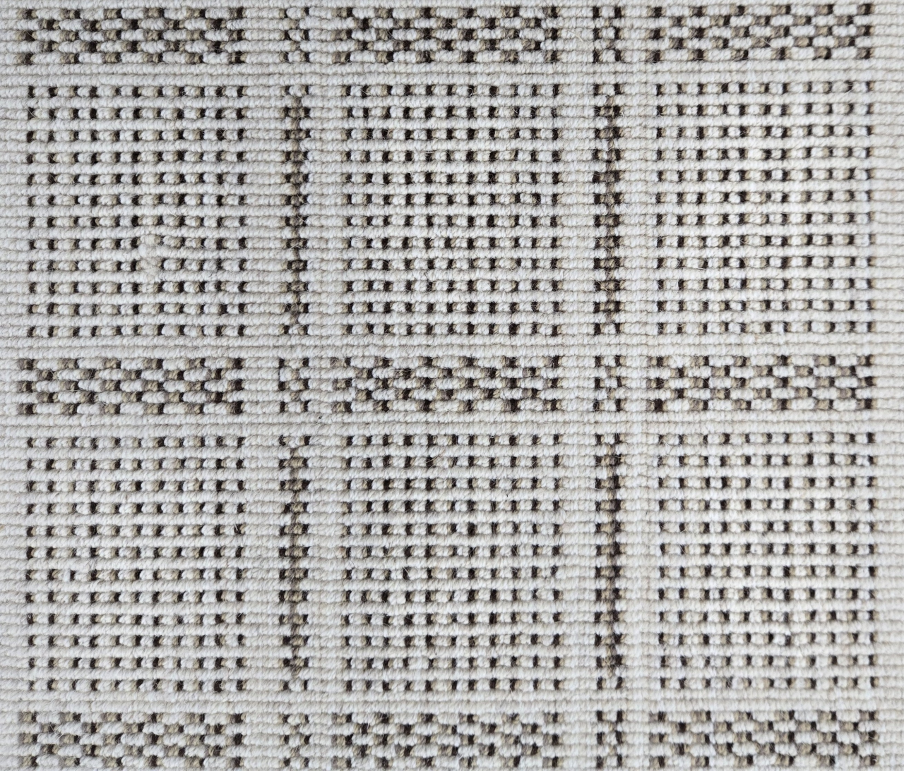 Broadloom carpet in check pattern in shades of brown with cream. 