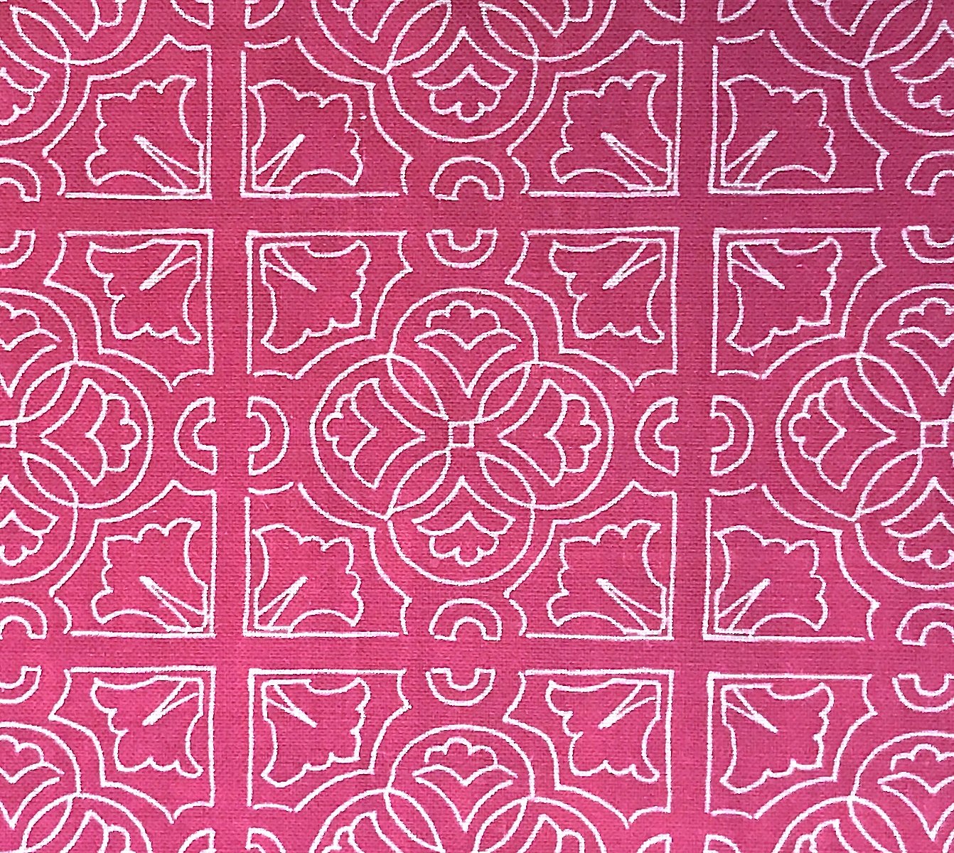 Detail of fabric in a damask lattice print in white on a fuchsia field.