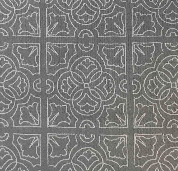 Detail of fabric in a damask lattice print in light gray on a gray field.