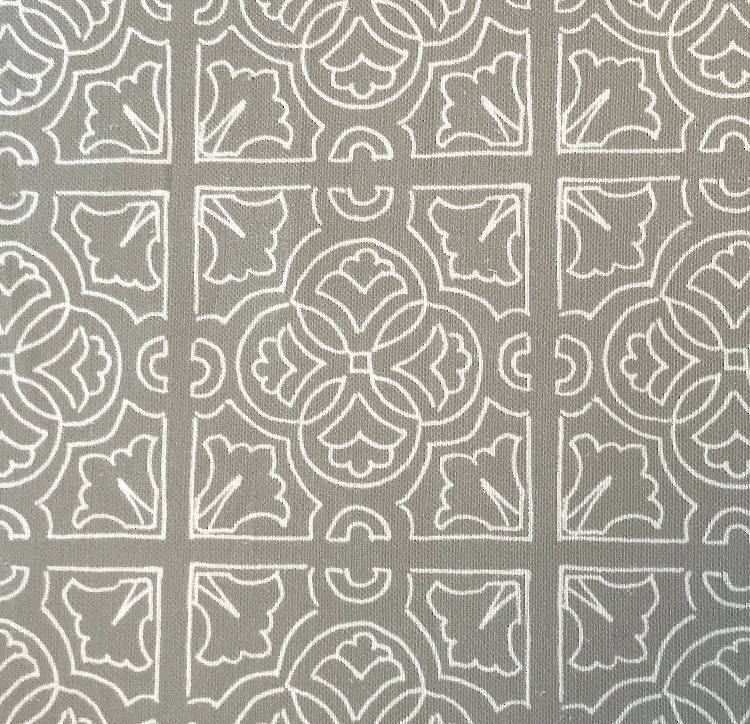 Detail of fabric in a damask lattice print in white on a gray field.