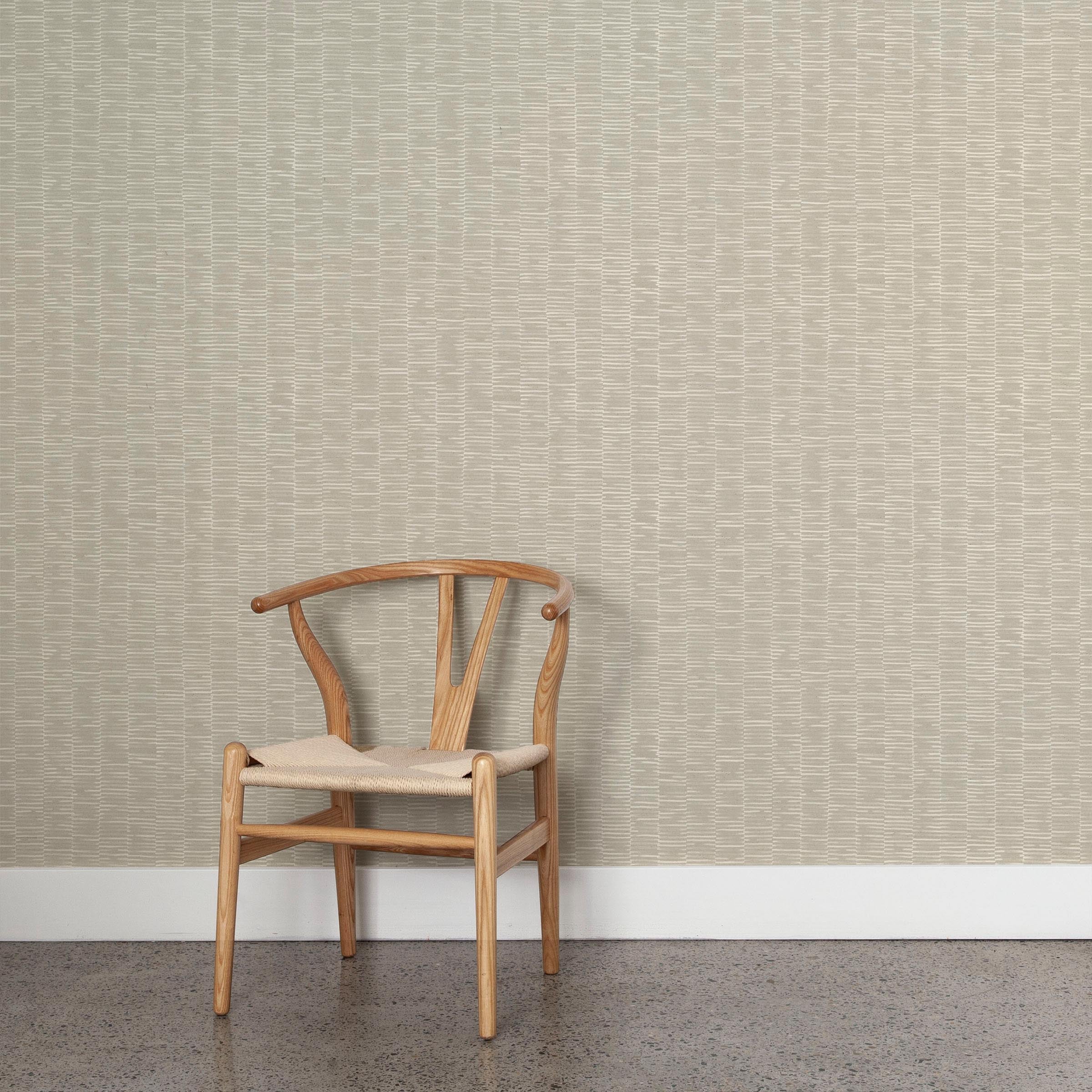 A wooden chair stands in front of a wall papered in a small-scale checked pattern in shades of cream and gray.