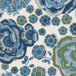 Detail of fabric in a floral print in shades of blue, green and tan on a white field.