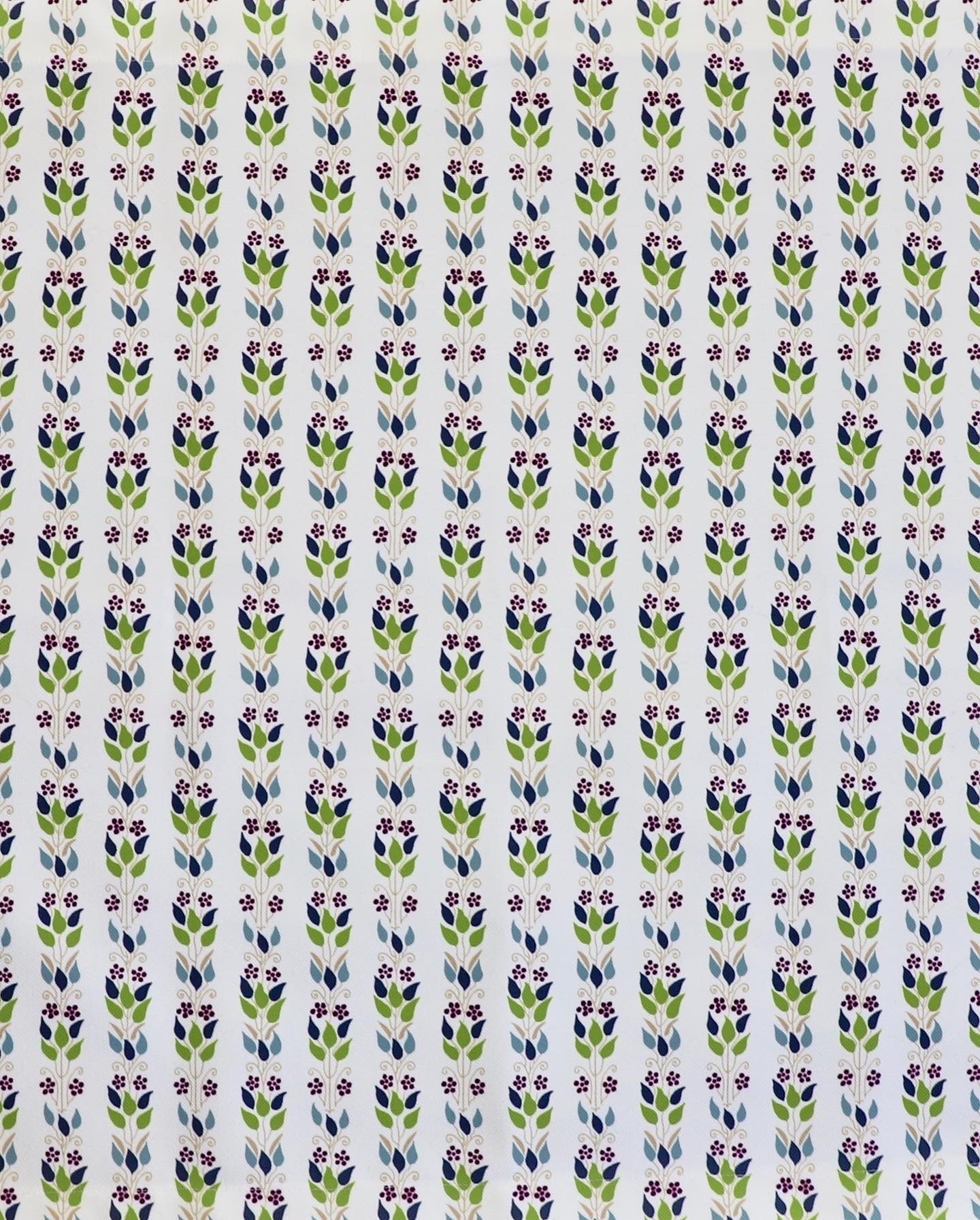 Detail of fabric in a striped botanical print in shades of blue, purple and green on a cream field.