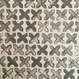 Close-up of fabric in a repeating "X" print in gray on a white field.