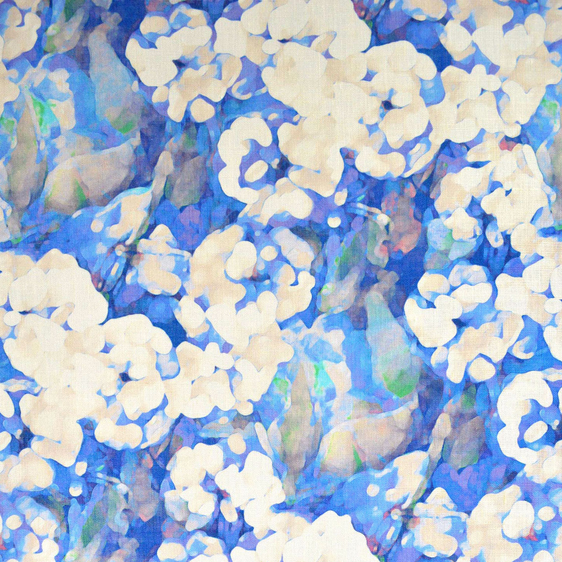 Detail of fabric in an abstract floral print in technicolor shades of blue, cream and green.