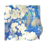 Square fabric swatch in an abstract floral print in technicolor shades of blue, cream and green.