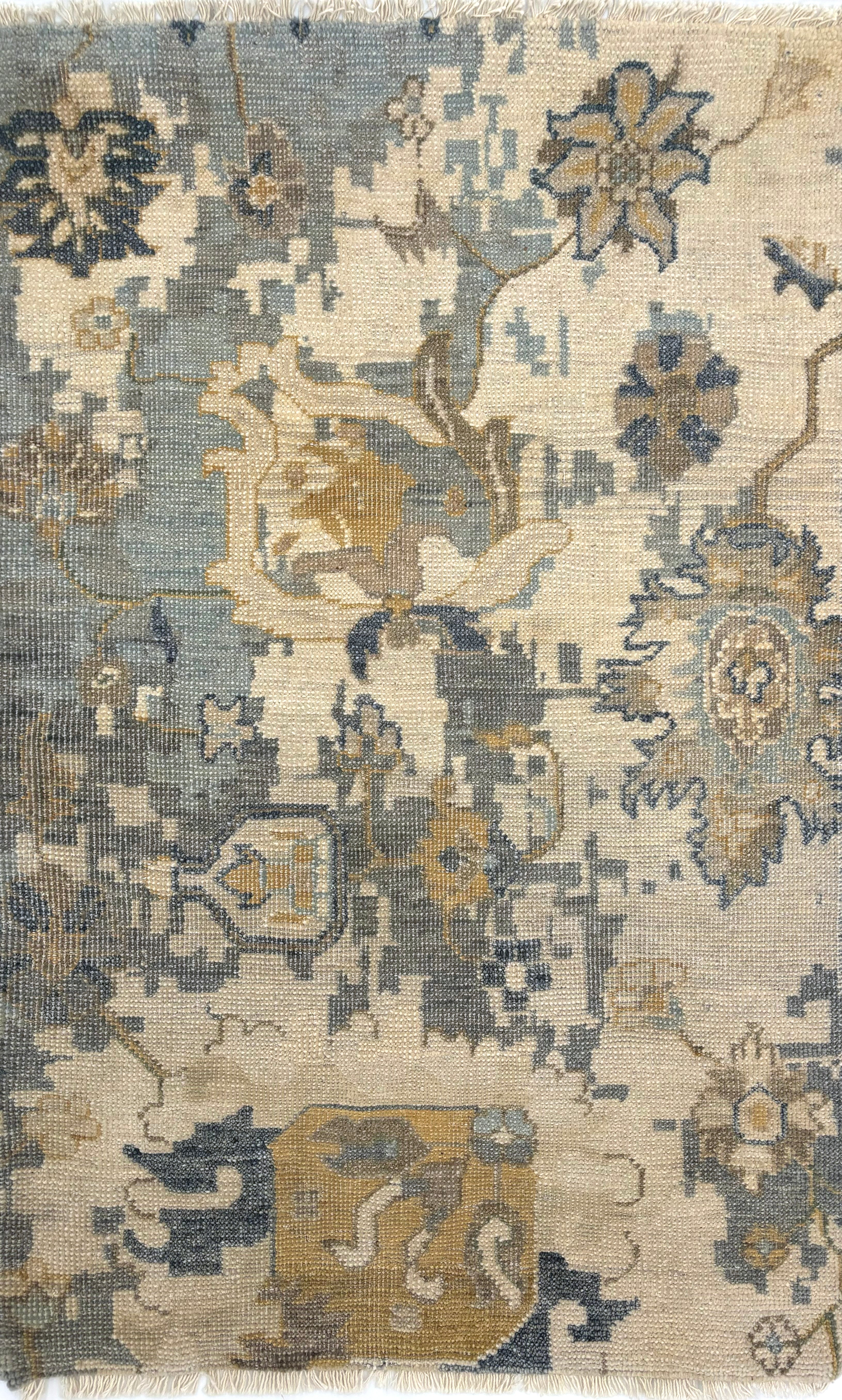 Handknotted carpet in an old word damask floral in shades of muted blue, cream and tan. 