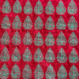 Detail of fabric woven in a repeating leaf print in shades of red and turquoise.