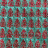 Detail of fabric woven in a repeating leaf print in shades of red and turquoise.