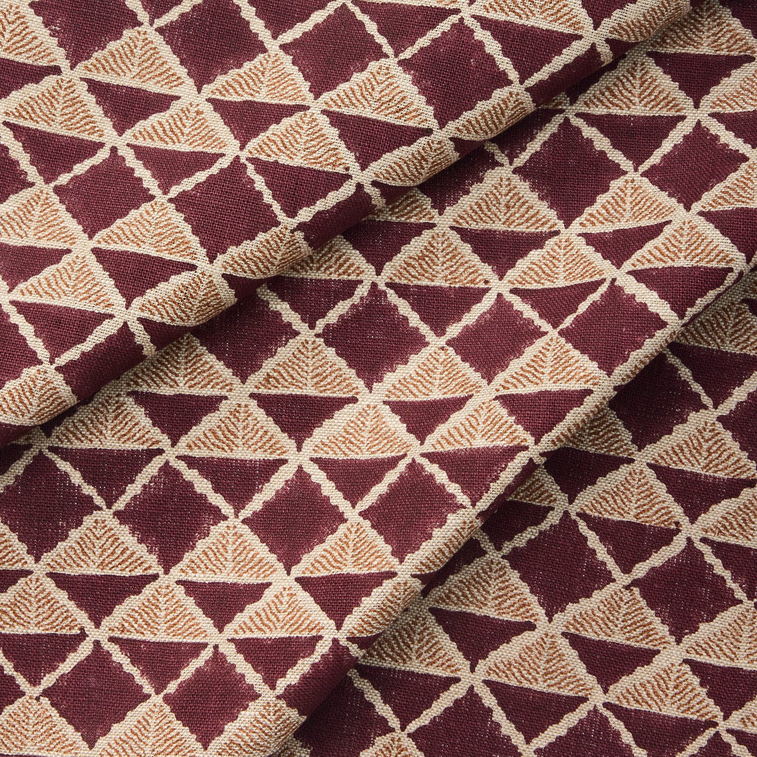 Draped fabric with a geometric pattern of triangles in wine purple and brown.