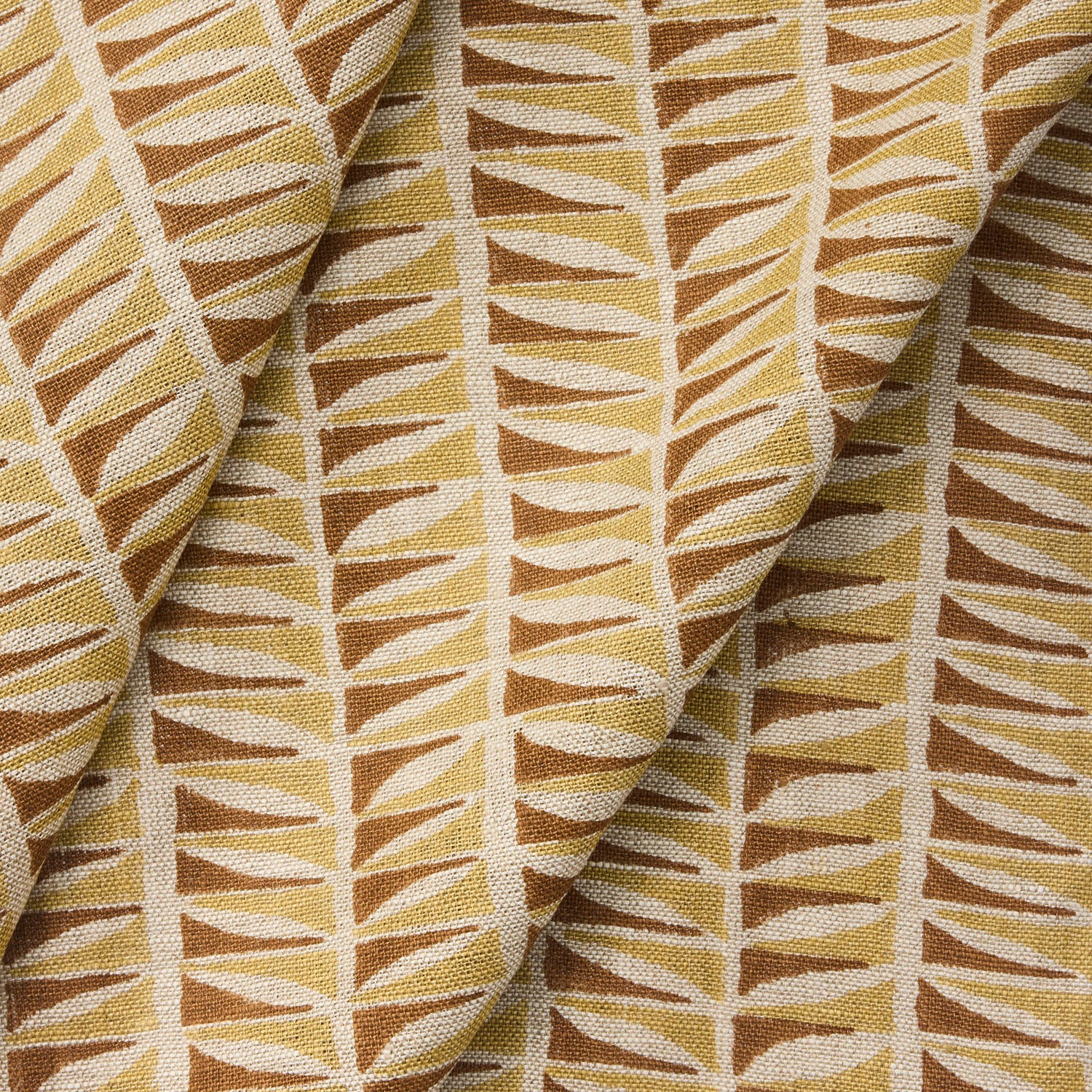 Draped close-up of fabric with a geometric leaf pattern in brown and beige.