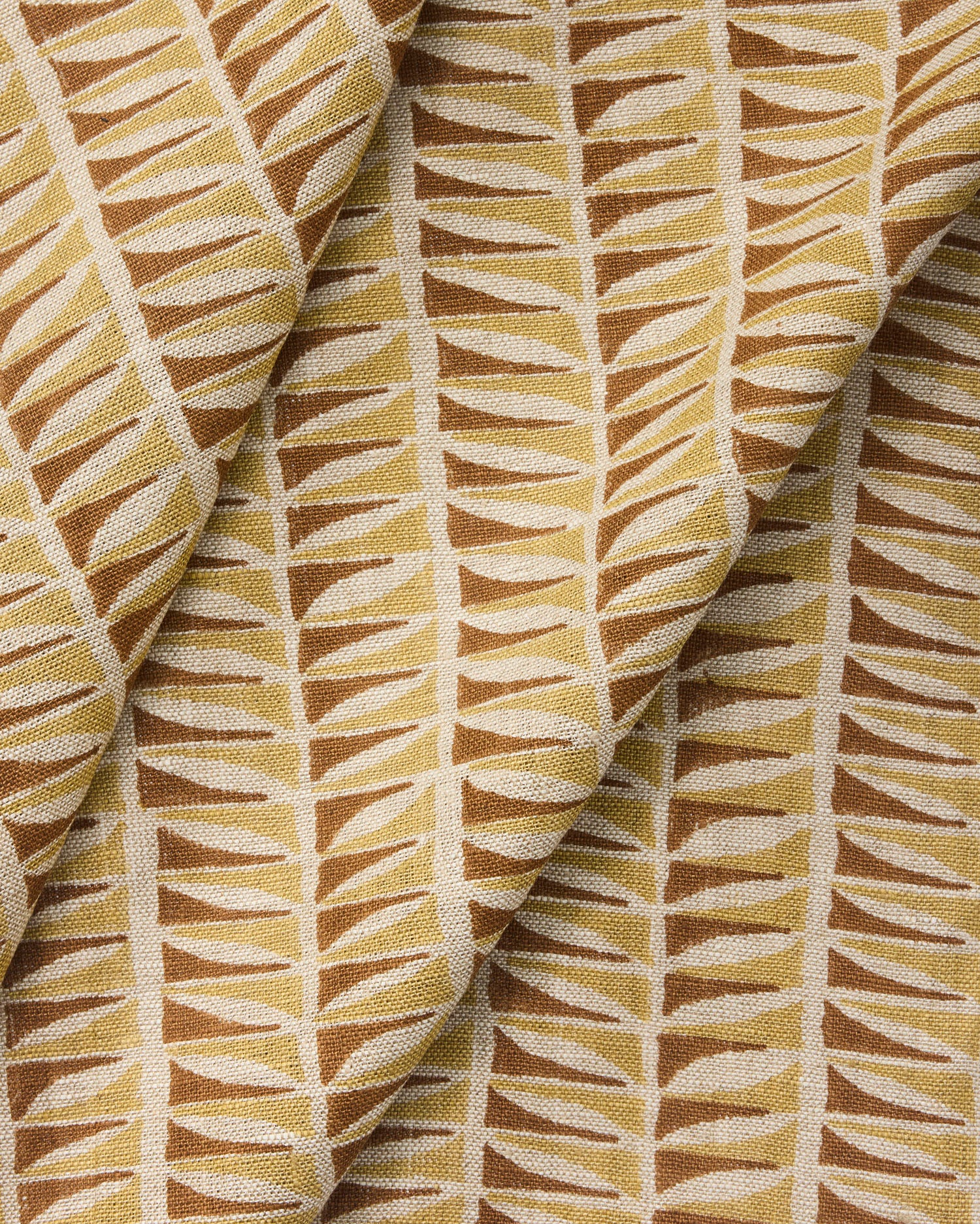 Draped close-up of fabric with a geometric leaf pattern in brown and beige.