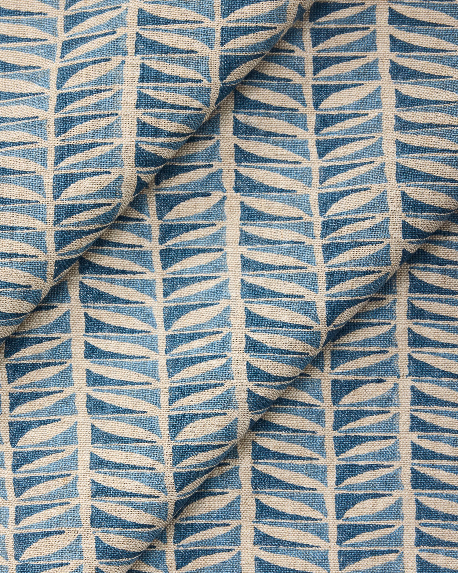 Draped close-up of fabric with a geometric leaf pattern in blue.