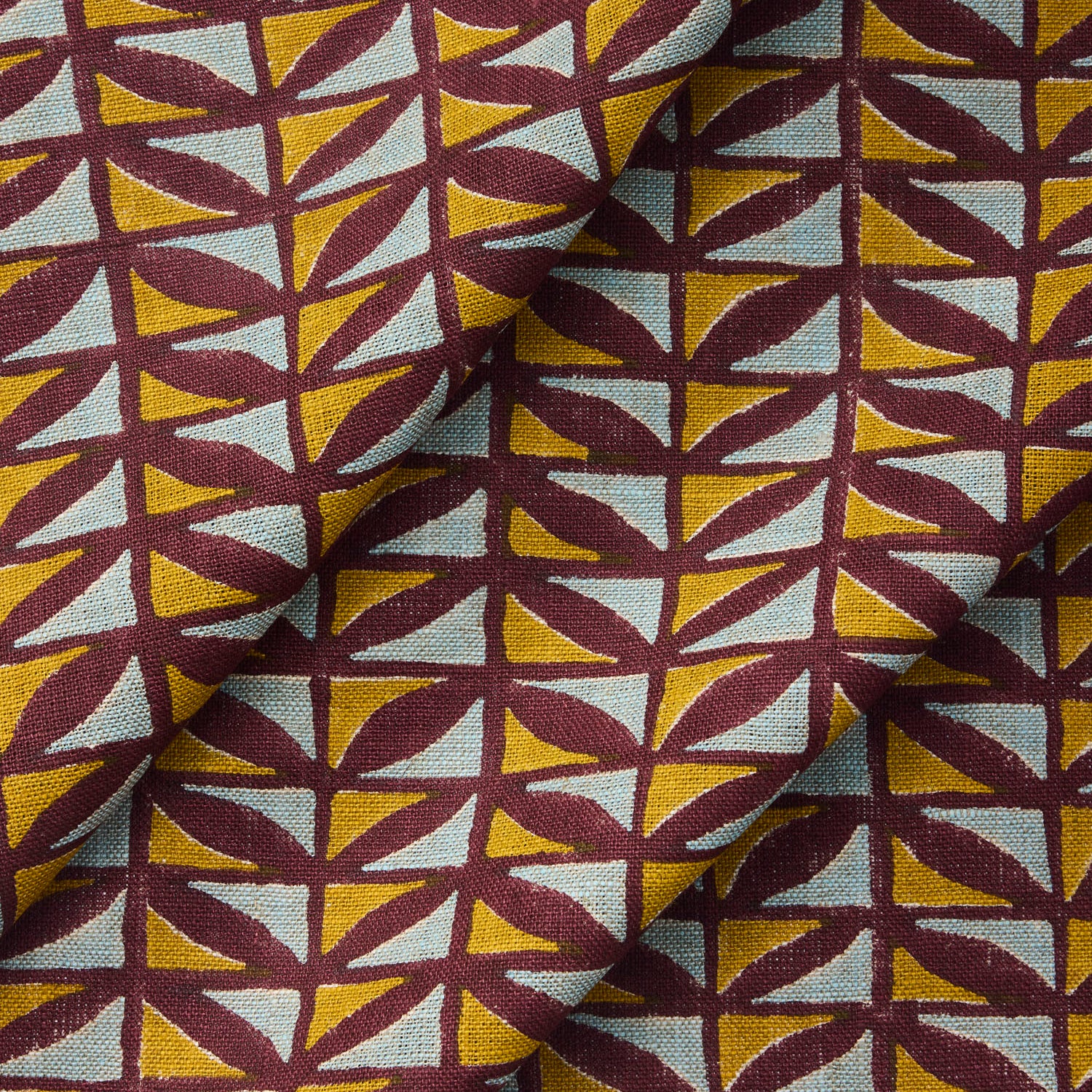 Draped fabric with a geometric pattern of triangles in yellow, and blue on a purple field.