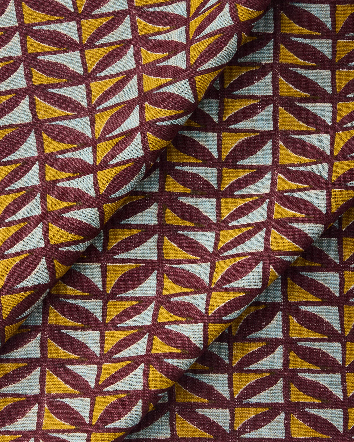 Draped fabric with a geometric pattern of triangles in yellow, and blue on a purple field.