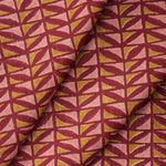 Draped close-up of fabric with geometric pattern in pink and ochre on a crimson field. 