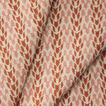 Draped fabric with a abstract leaf pattern in red and pink on a neutral background