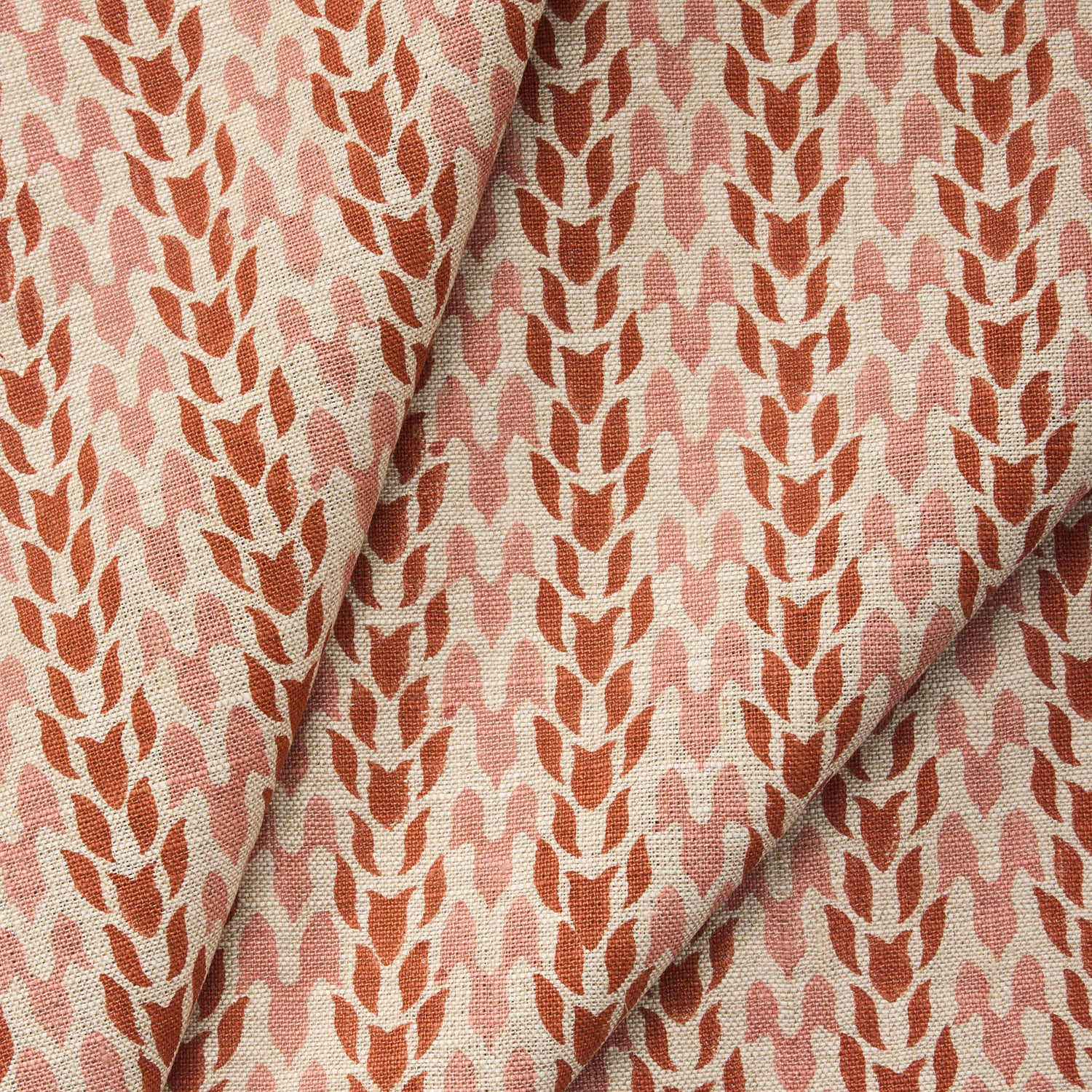 Draped fabric with a abstract leaf pattern in red and pink on a neutral background