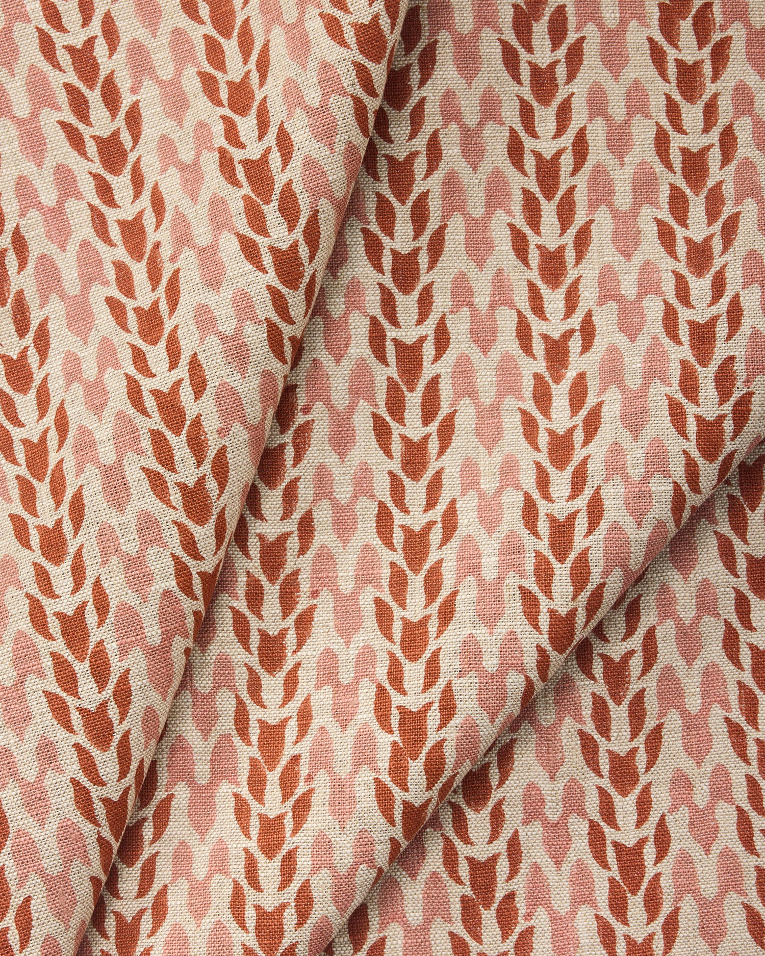 Draped fabric with a abstract leaf pattern in red and pink on a neutral background