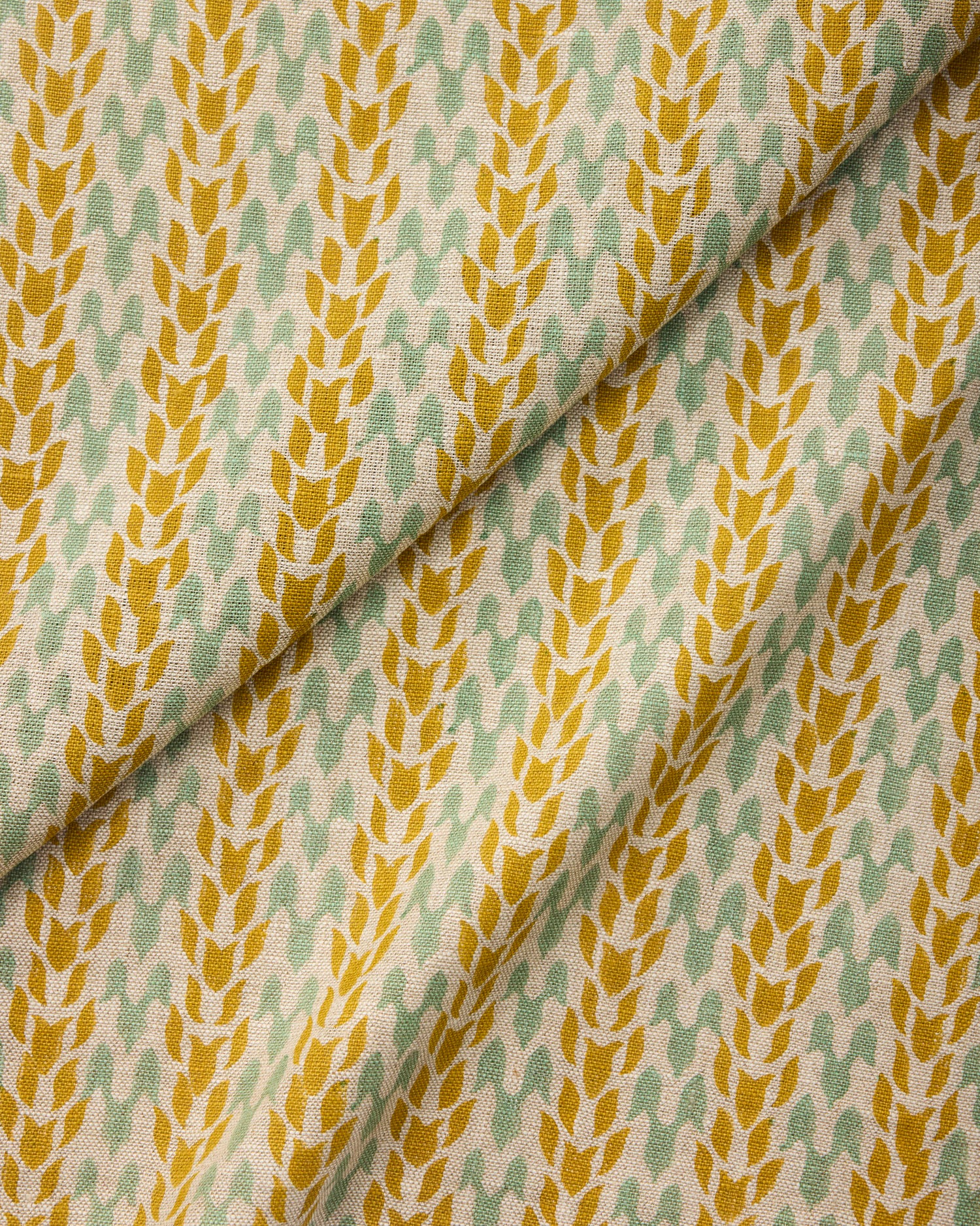 Draped fabric with a pattern of yellow and green leaves on a neutral background