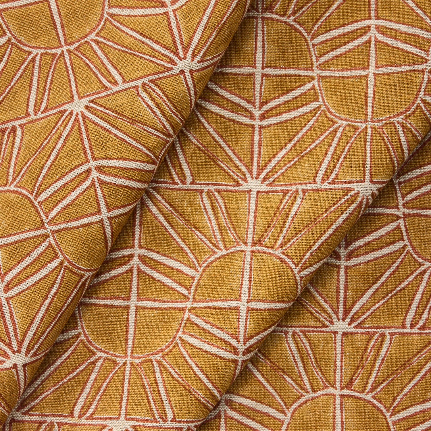 Draped fabric with geometric sun pattern in warm yellow and rust.