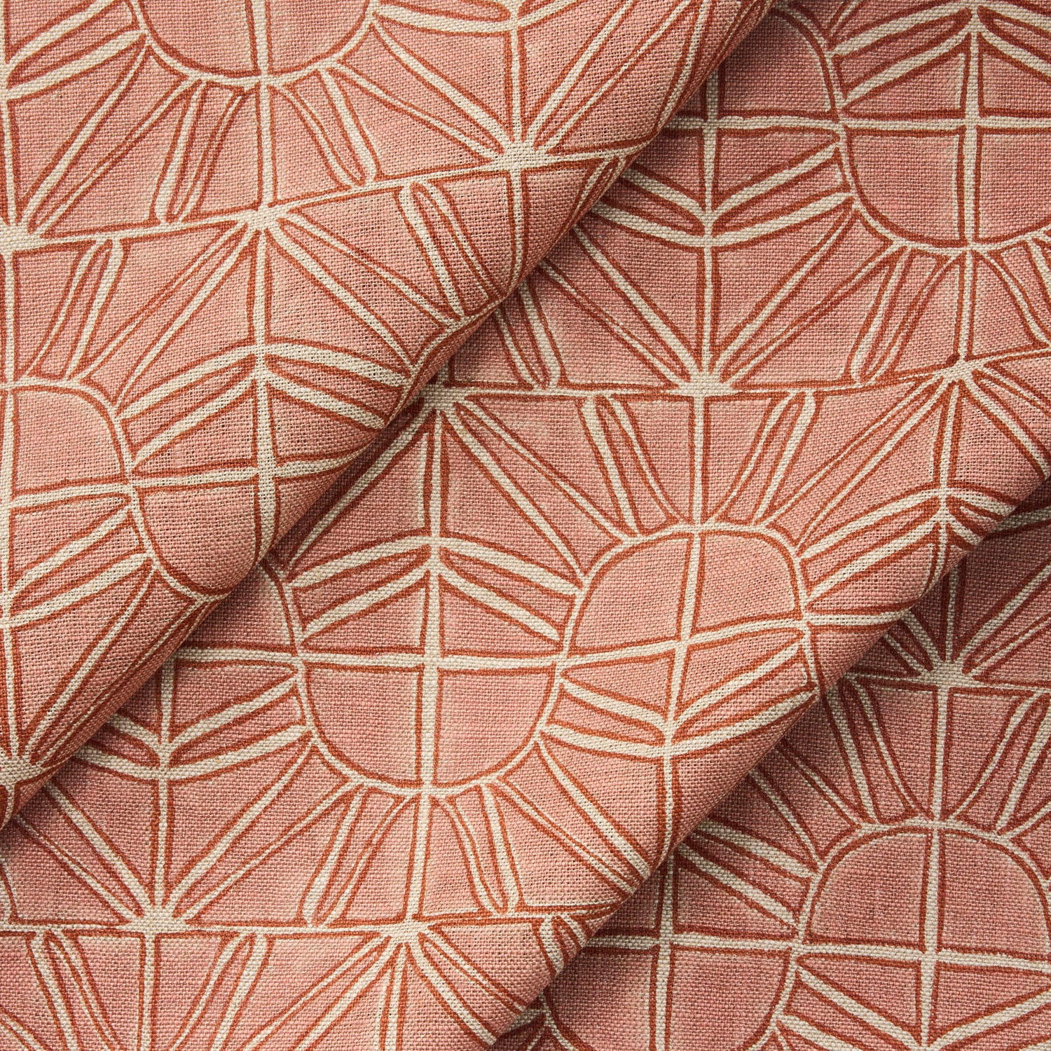 Draped fabric with geometric sun pattern  in clay pink and rust red.