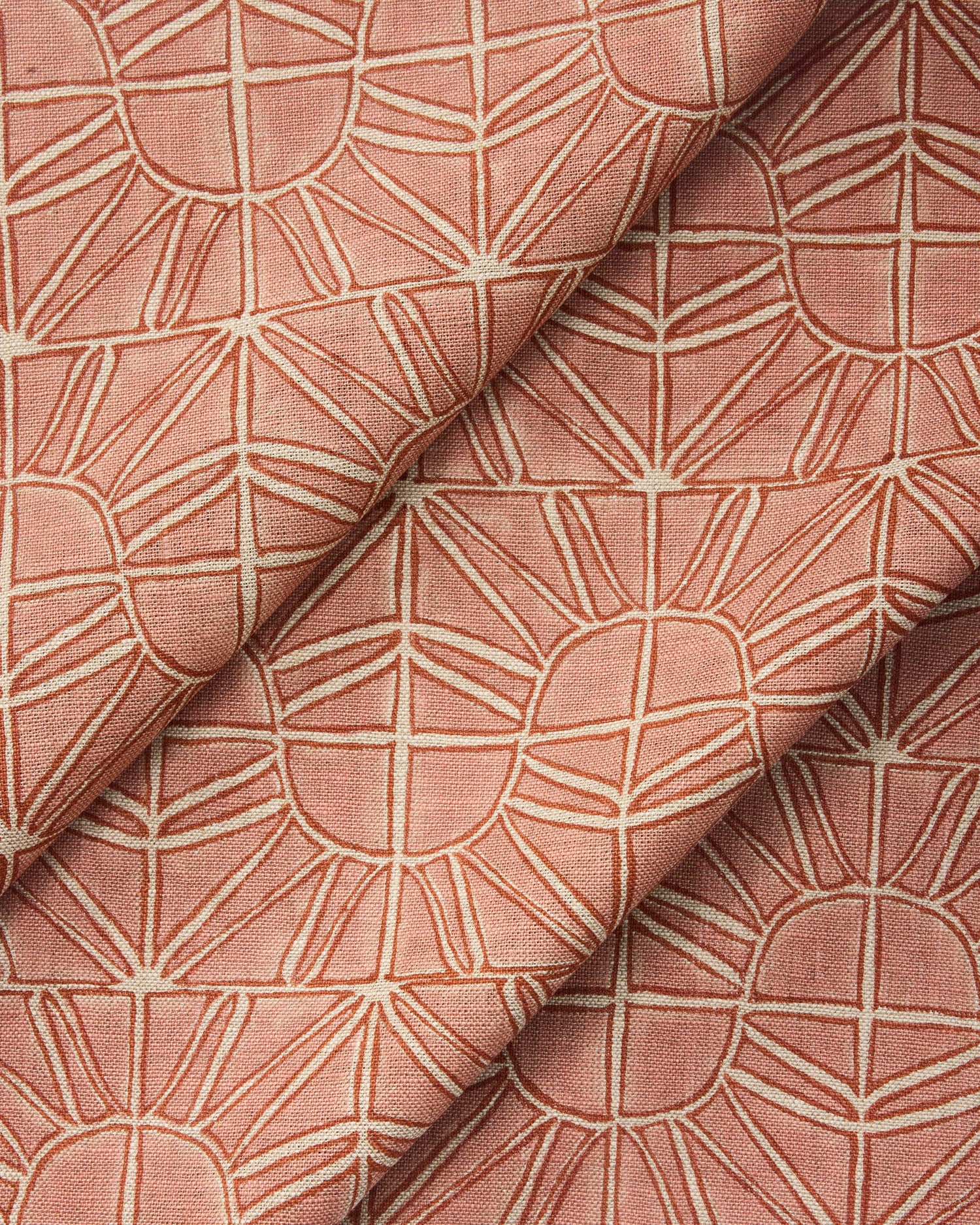 Draped fabric with geometric sun pattern  in clay pink and rust red.
