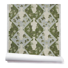 Partially unrolled wallpaper in a large, painterly vase and leaf print over a repeating diamond background in shades of green and blue.