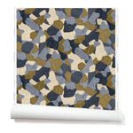 Partially unrolled wallpaper in a painterly geometric pattern in shades of blue, cream and olive.