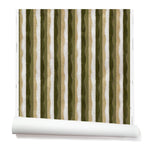 Partially unrolled wallpaper in a curvy hand-painted stripe pattern in olive, sage, white and gold.
