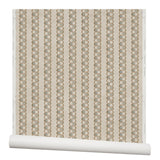 Partially unrolled wallpaper in a repeating mosaic stripe print in shades of brown and gray-blue on a tan field.